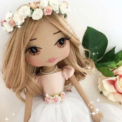 personalised handmade doll with hand embroidered brown eyes and long blonde hair, wearing a pink and white christening dress and a flower and swarovski crystal flower crown