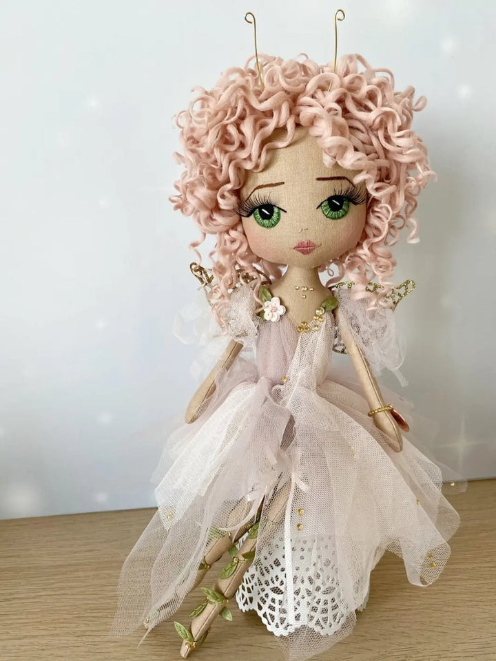 Pink handmade fairy doll with embroidered face. Featuring gold fairy wings, green eyes, pink hand rolled curly hair