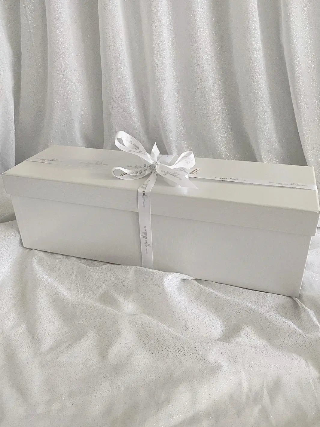 full length image of white gifting box with gold logo & white satin ribbon for Upper Dhali handmade dolls