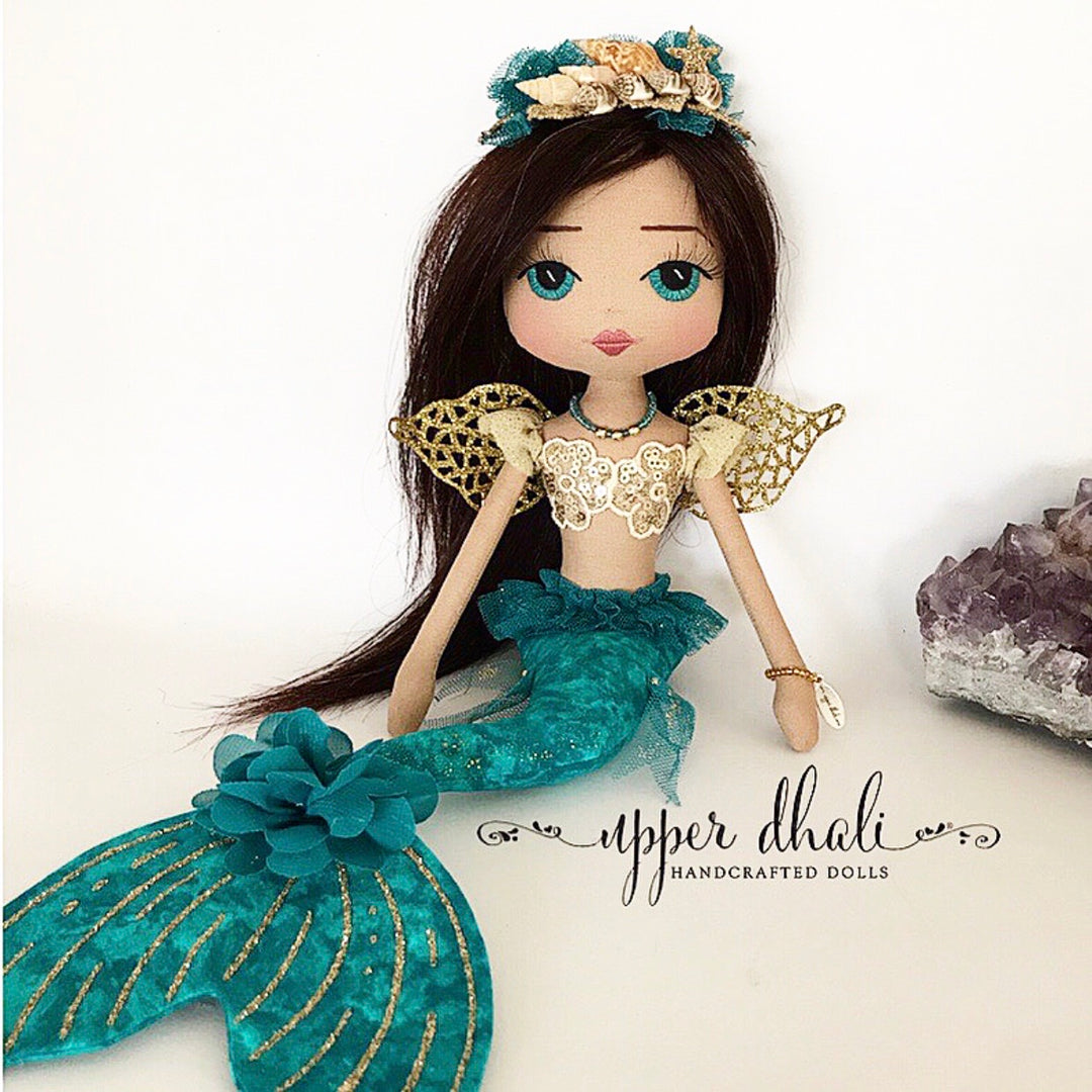 mermaid doll with a teal and gold tail, long dark hair and a shell tiara