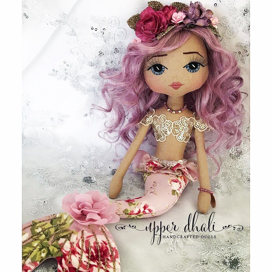 purple mermaid doll with a gold bodice and blue hand embroidered eyes with purple curly hair