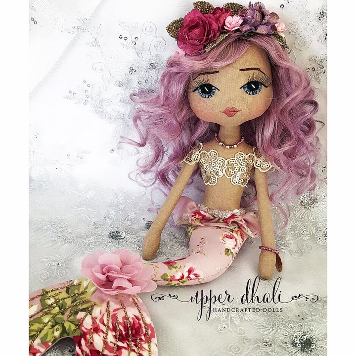 purple mermaid doll with a gold bodice and blue hand embroidered eyes with purple curly hair