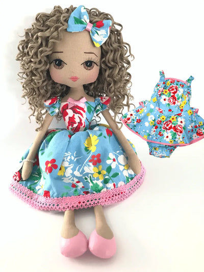 Upper Dhali personalised portrait doll wearing a blue floral dress with curly brown hair with the baby outfit the dress was made from