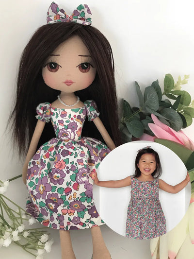 Upper Dhali personalised handmade doll wearing a puple liberty print dress with long dark hair and brown eyes. Image insert is of a young girl wearing the same dress.